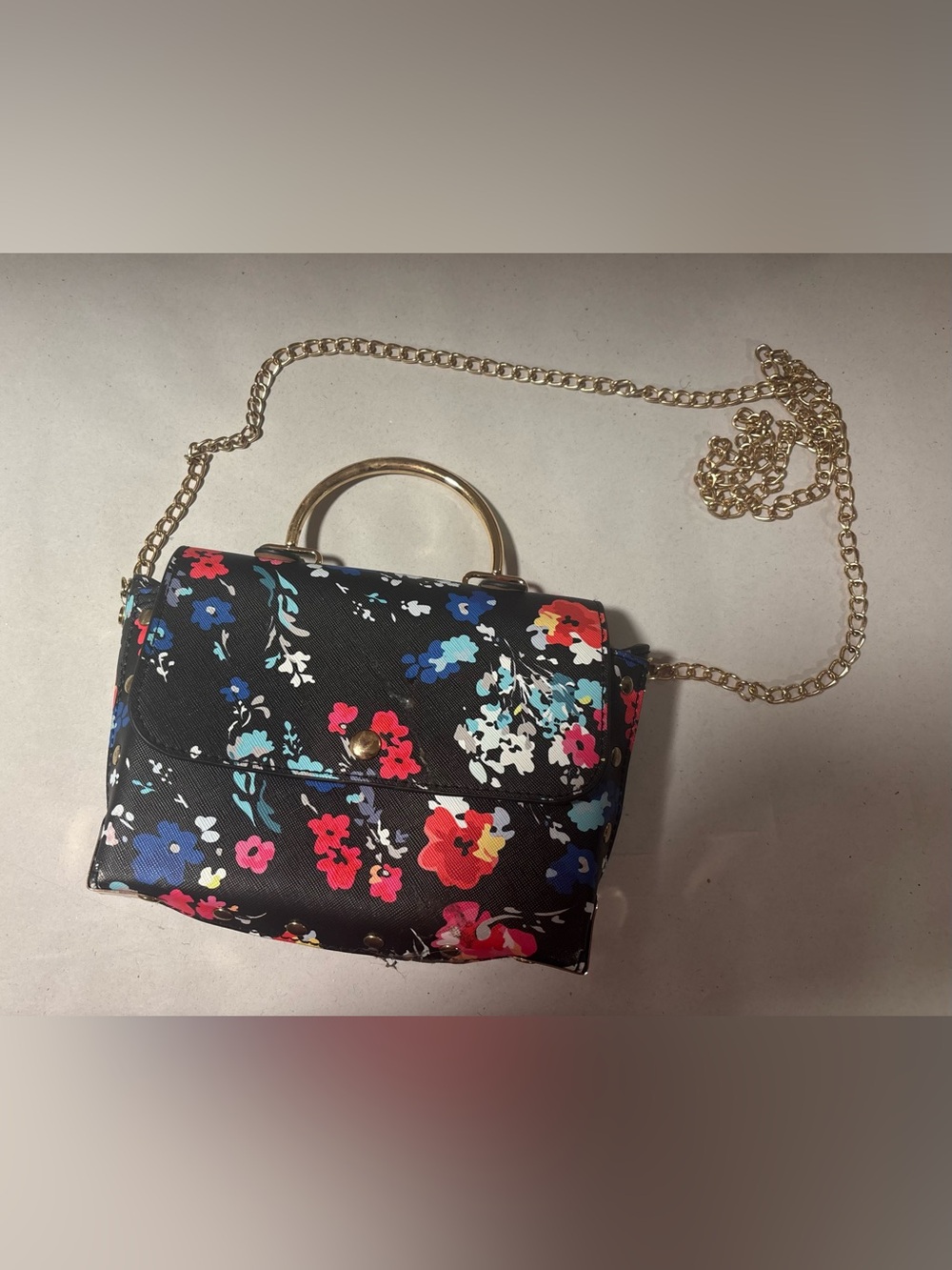 black mini handbag with vibrant multicolored floral print and gold tone handle